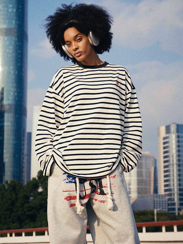 HypeCord men’s black and white horizontal striped long-sleeve T-shirt, styled with a red beanie and burgundy wide-leg trousers.