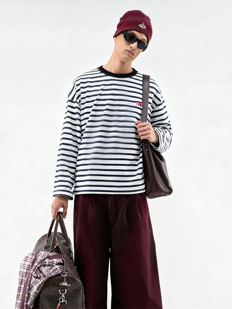 FDR Studios men’s black and white horizontal striped long-sleeve T-shirt, oversized fit, styled with burgundy trousers and a tote bag for a high-street look.