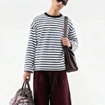 FDR Studios men’s black and white horizontal striped long-sleeve T-shirt, oversized fit, styled with burgundy trousers and a tote bag for a high-street look.