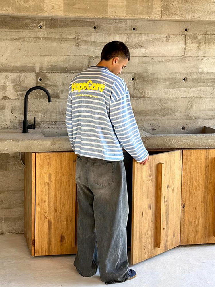 Model in an industrial interior setting wearing HypeCord light blue striped shirt and dark grey jeans.