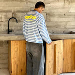 Model in an industrial interior setting wearing HypeCord light blue striped shirt and dark grey jeans.