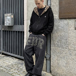 Male model in FDR black leopard hoodie and baggy graphic trousers in urban setting.