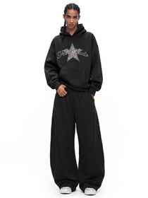 Full-length view of a streetwear outfit featuring a black baggy hoodie with star logo and oversized wide-leg pants.