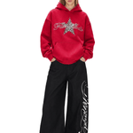 Model showcasing a red Y2K oversized hoodie with a star graphic paired with black baggy wide-leg trousers.