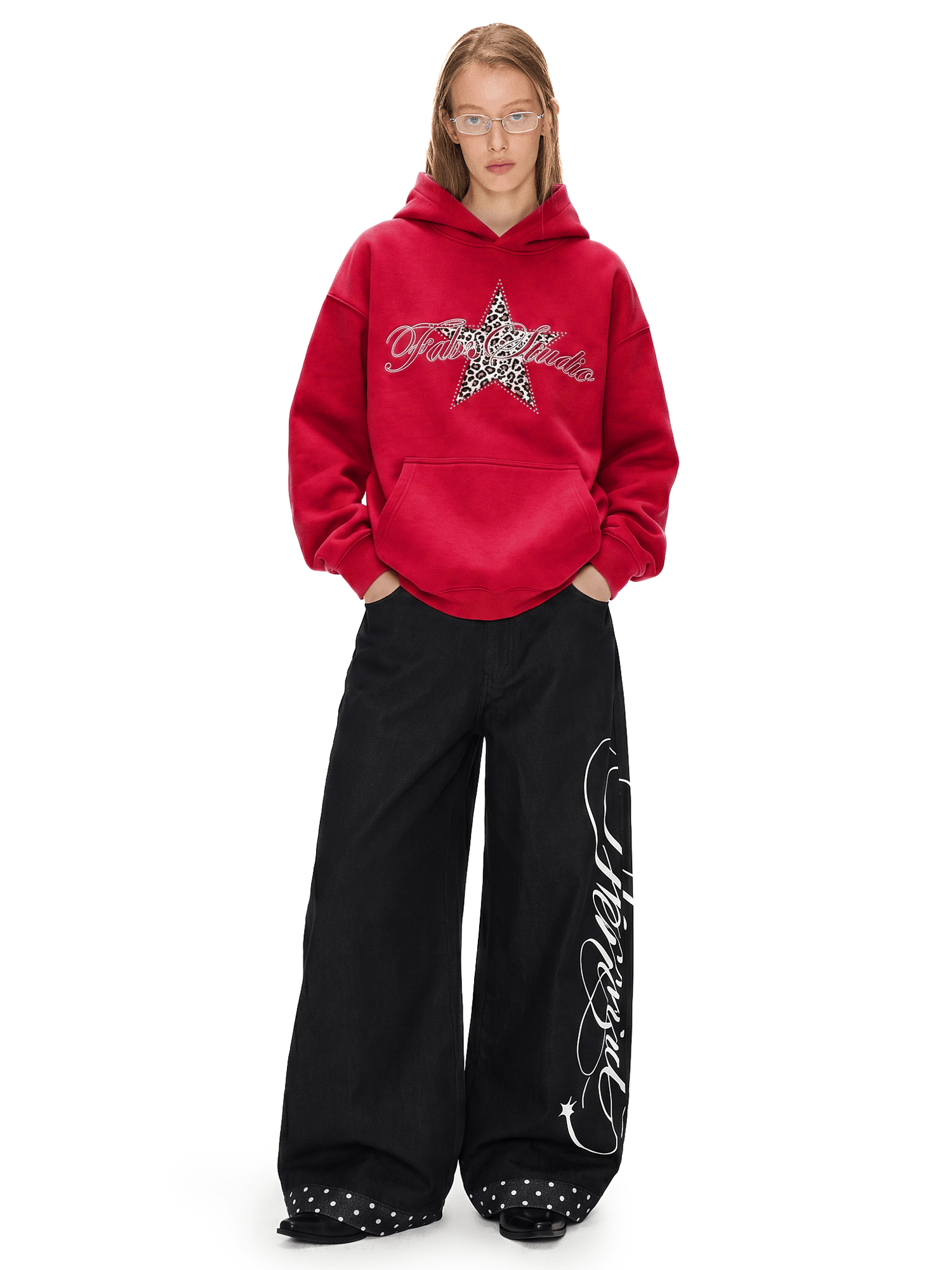 Model showcasing a red Y2K oversized hoodie with a star graphic paired with black baggy wide-leg trousers.