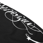 Macro shot of white cursive script embroidery and star graphic on black fabric.