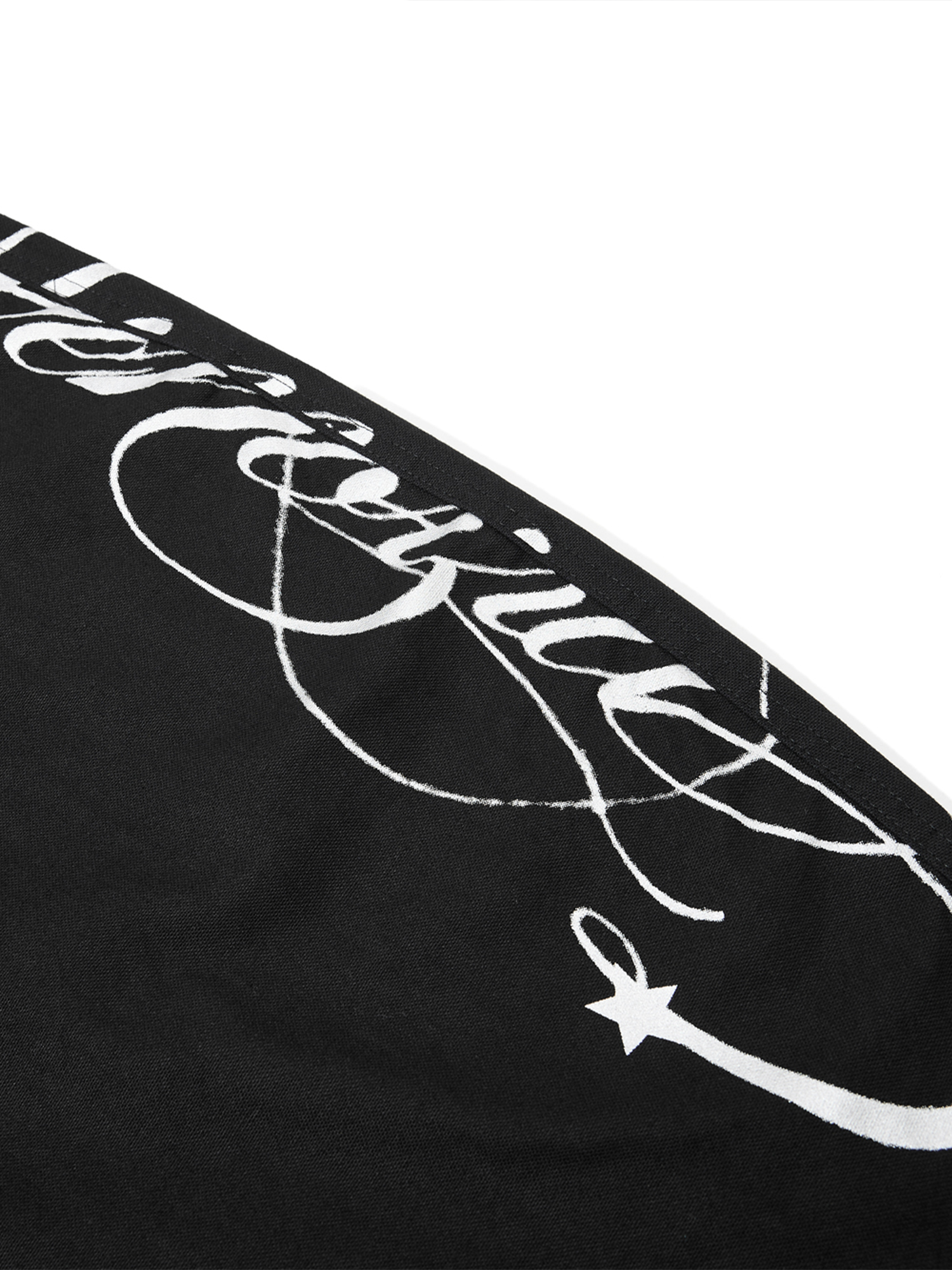 Macro shot of white cursive script embroidery and star graphic on black fabric.