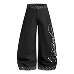 Angled view of black oversized trousers highlighting the white artistic script embroidery on the side.