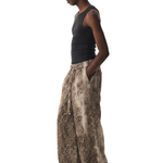 Side profile of a model wearing baggy leopard print trousers and a black tank top, showcasing the loose silhouette.