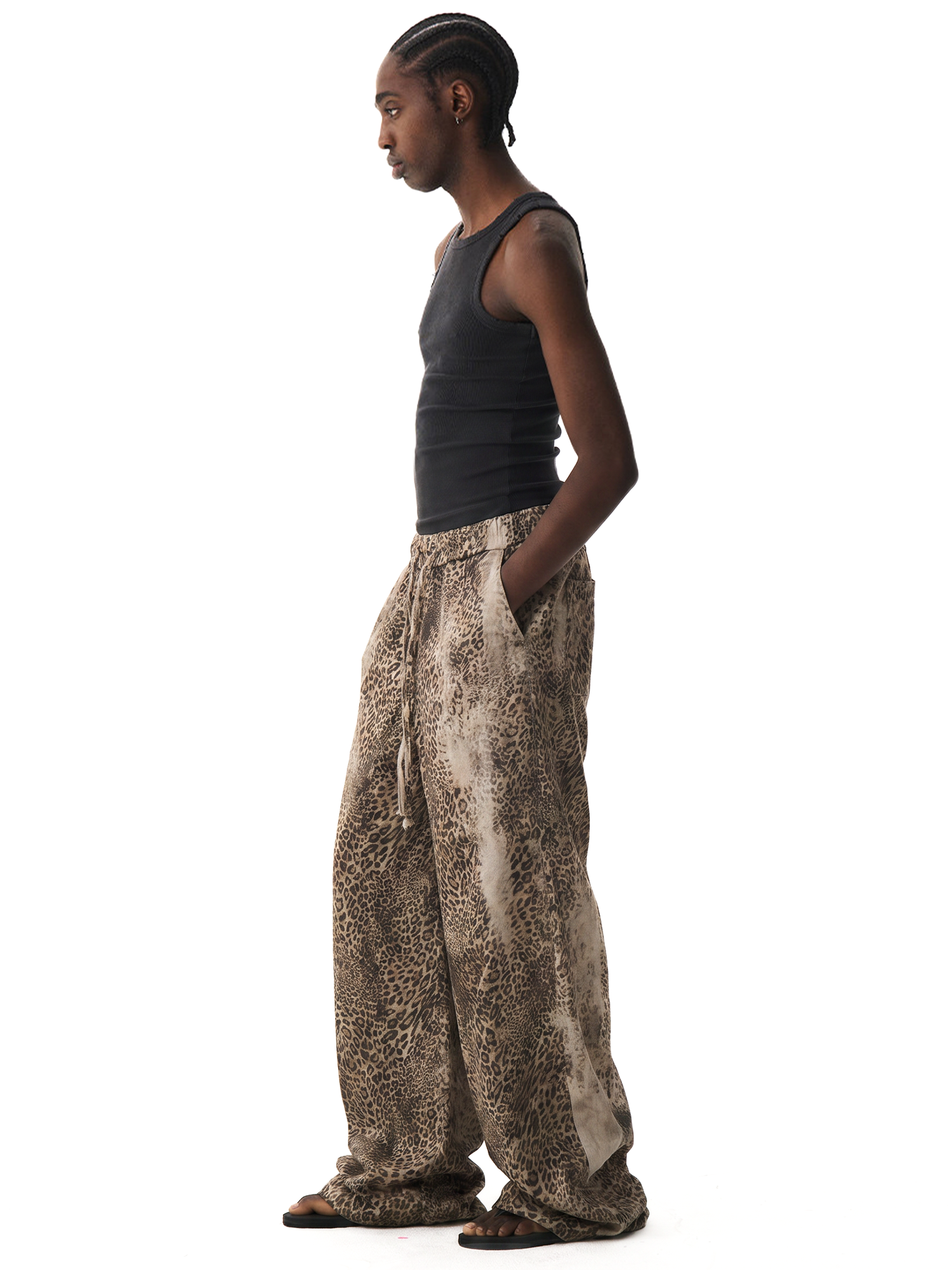 Side profile of a model wearing baggy leopard print trousers and a black tank top, showcasing the loose silhouette.