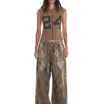 Full-length front view of a model wearing a brown sleeveless graphic zip-up top and oversized leopard print drawstring trousers.