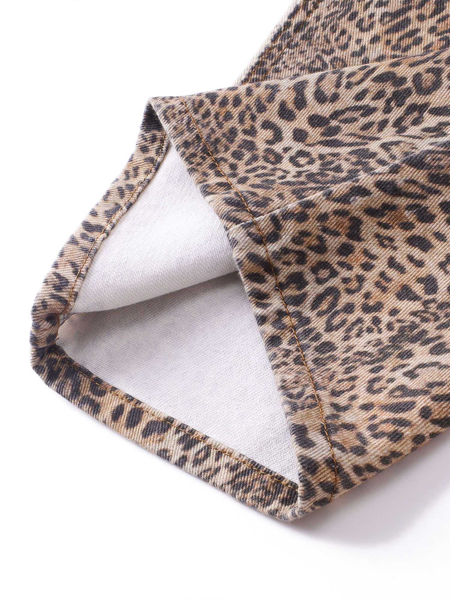 Close-up detail of the leg opening hem on the leopard print trousers, highlighting the fabric texture and inner lining.