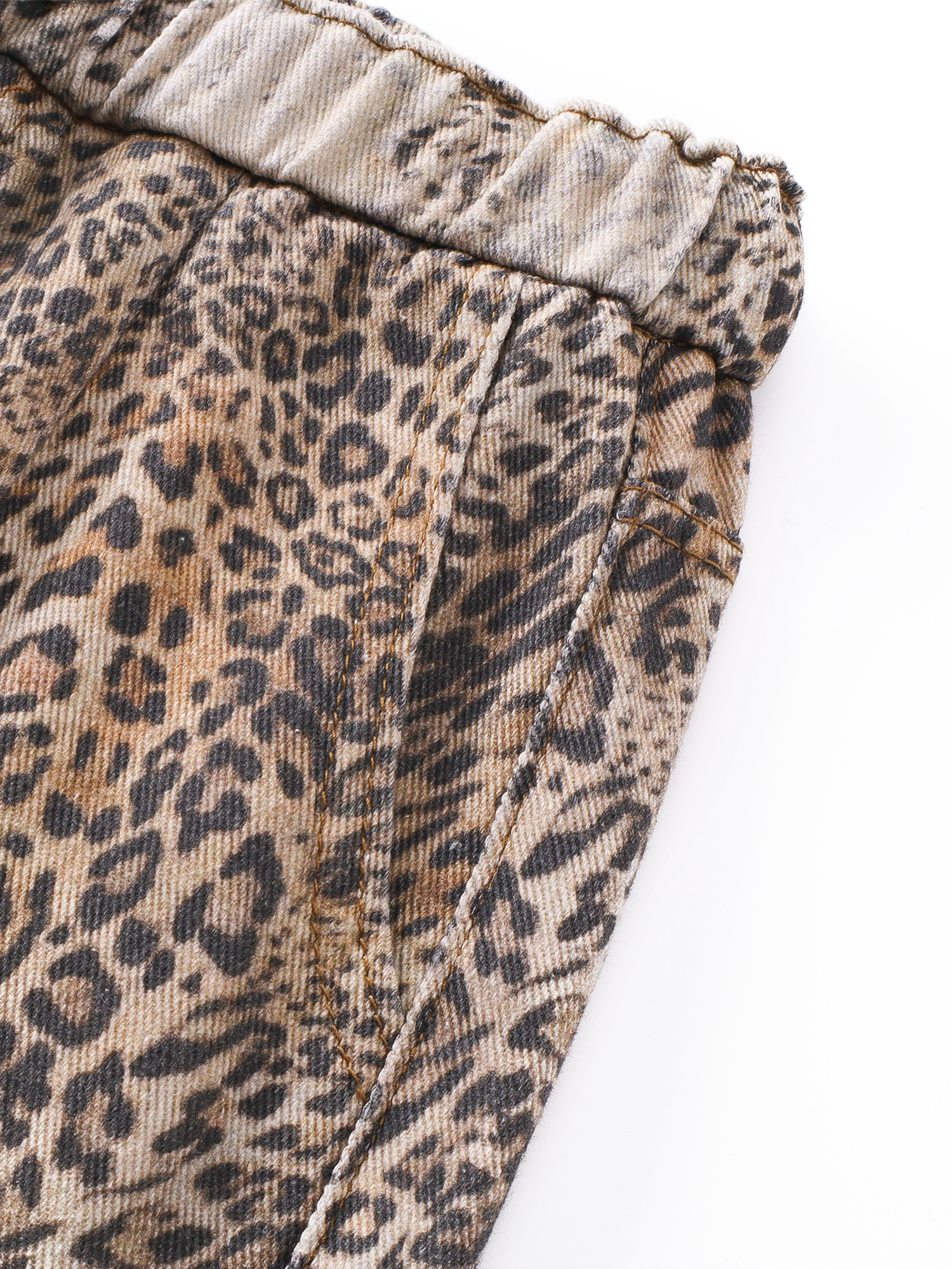 Macro shot of the leopard print fabric and side pocket detail of the oversized trousers.