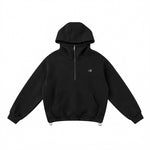 Close-up of female model in black high-neck hoodie with embroidered chest logo and functional kanga pocket.