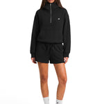 Model wearing black oversized FDR half-zip hoodie and matching sweat shorts with high neck zipped up.