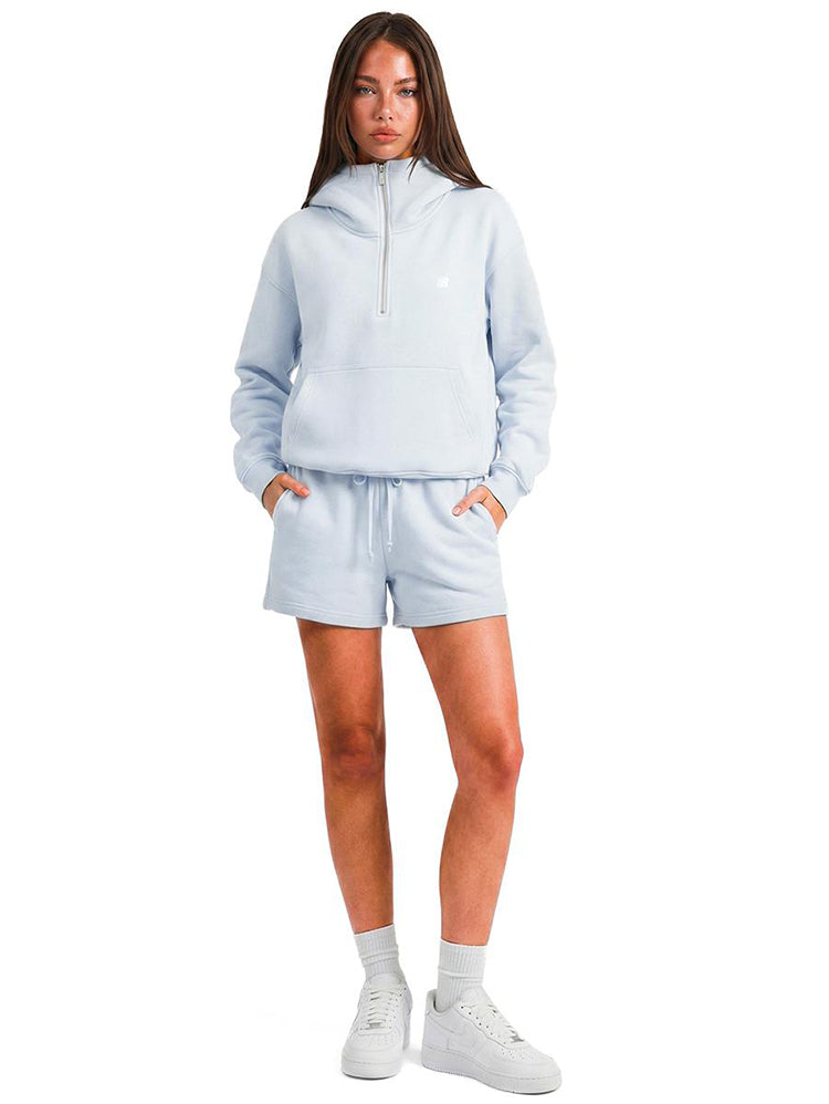 Model wearing the FDR half-zip hoodie in light blue with matching lounge shorts and white socks.