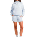 Model wearing the FDR half-zip hoodie in light blue with matching lounge shorts and white socks.