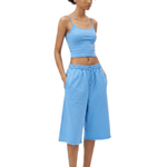 Full-body front view of a model wearing a lake blue spaghetti-strap camisole cropped top and matching sky blue loose knee-length shorts.