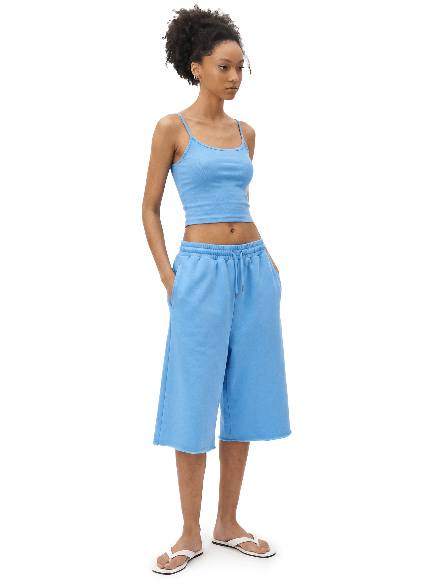 Full-body front view of a model wearing a lake blue spaghetti-strap camisole cropped top and matching sky blue loose knee-length shorts.
