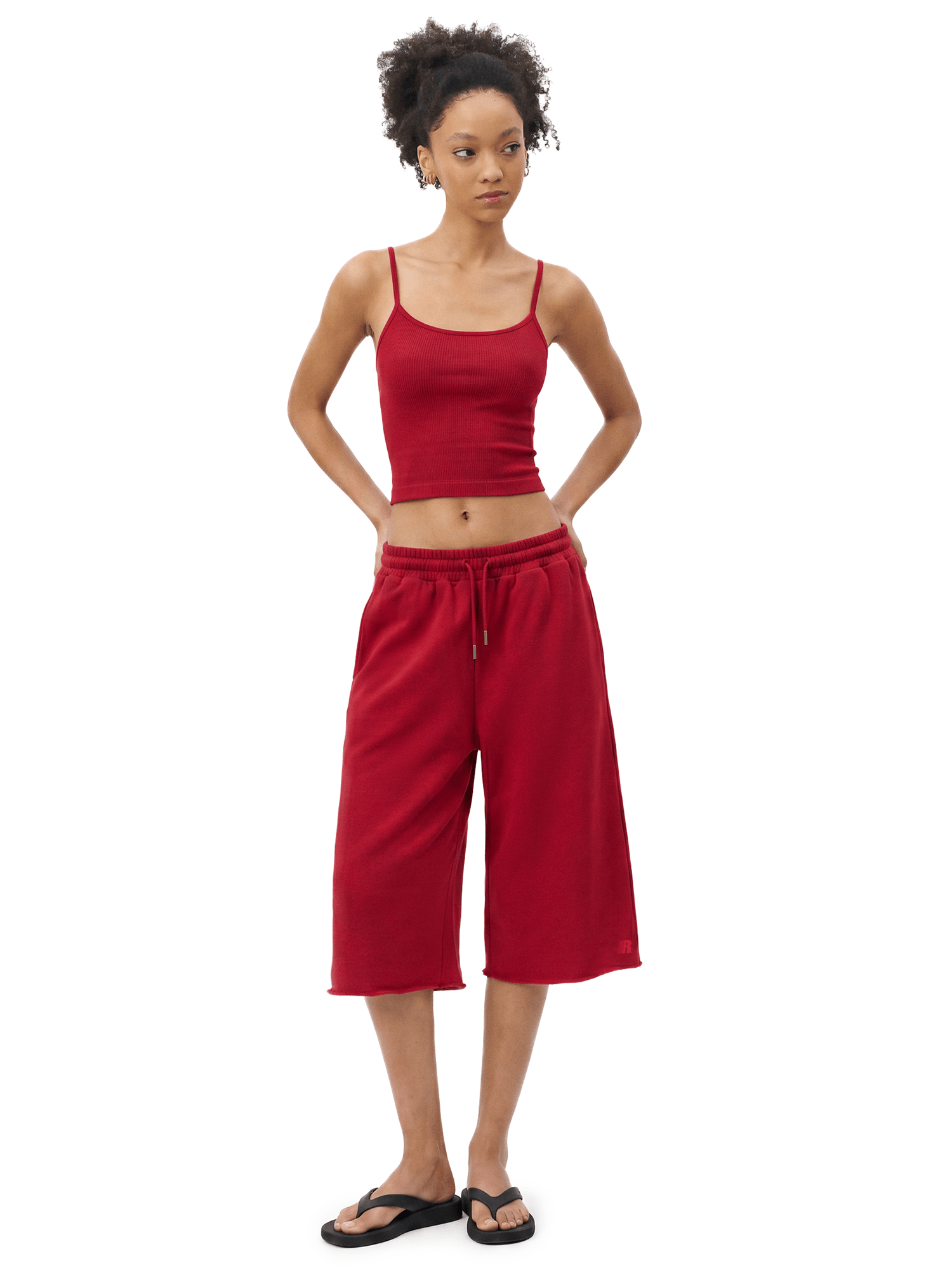 Full-body front view of a model wearing a dark red spaghetti-strap camisole cropped top and matching dark red loose knee-length shorts.