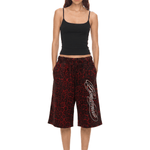 Woman wearing a black tank top and red patterned pants on a white background