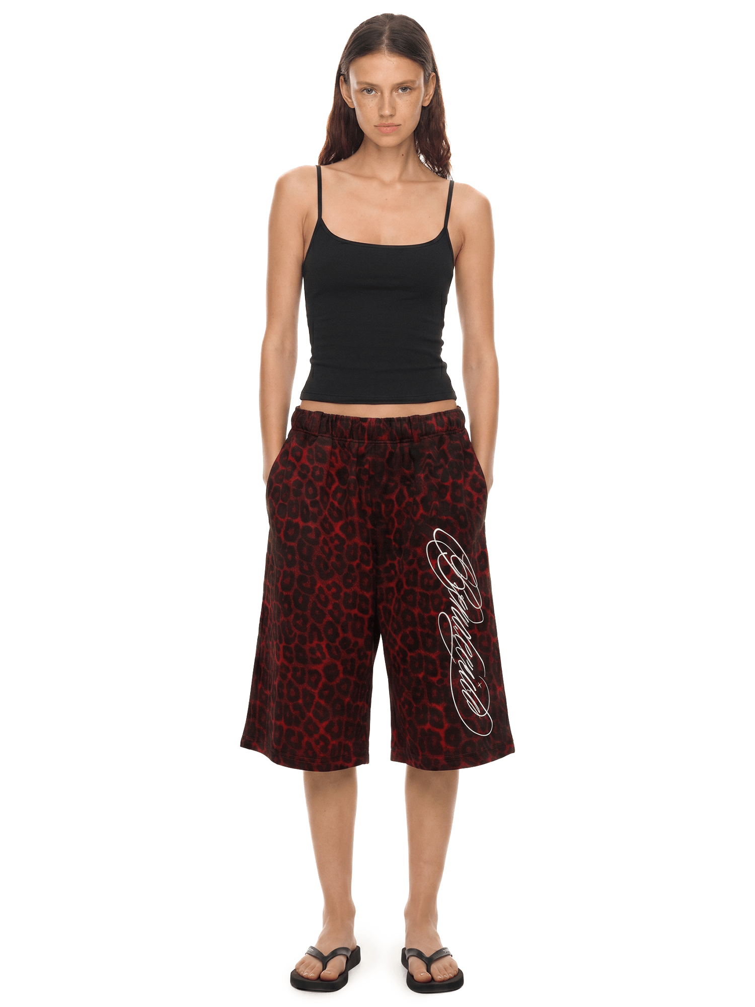 Woman wearing a black tank top and red patterned pants on a white background
