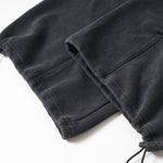 Detailed shot of the adjustable drawstring hem and toggle on black technical fabric pants.