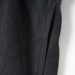 Close-up of dark gray fabric with a visible seam on a light background