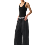 Side view of a female model styling black loose-fit athletic pants with a minimalist aesthetic.