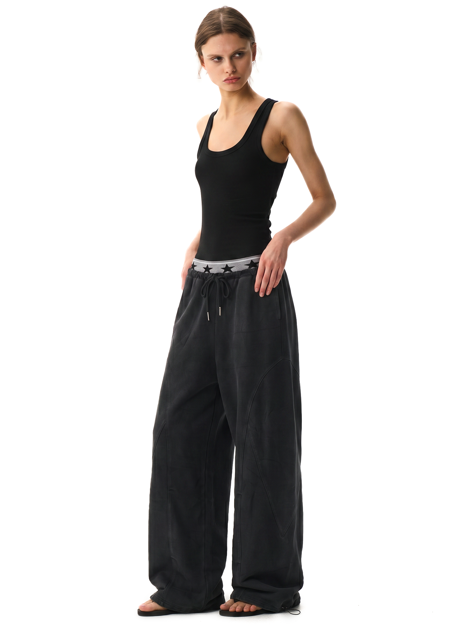 Side view of a female model styling black loose-fit athletic pants with a minimalist aesthetic.