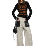 Lifestyle shot of a model wearing leopard print cargo pants with a black tank top and backpack.