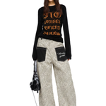 Female model styled in light khaki leopard print wide-leg pants and a black graphic long-sleeve tee.