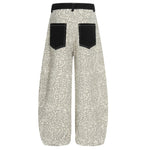 Close-up of the black pocket on leopard print pants featuring a white script brand logo.