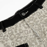 Close-up of the leopard print trouser waistband showing the black trim, metal button, and security tag.