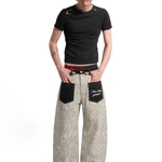 Male model wearing beige leopard print baggy trousers with a black t-shirt for a unisex urban aesthetic.