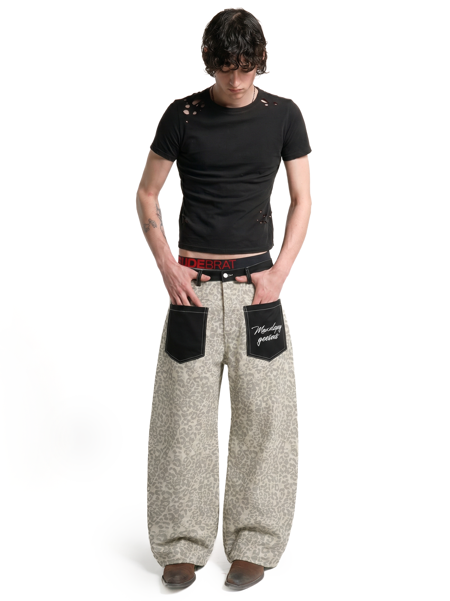Male model wearing beige leopard print baggy trousers with a black t-shirt for a unisex urban aesthetic.