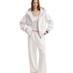 Front view of a model wearing a unisex off-white high-street streetwear tracksuit, featuring an oversized zip-up hoodie with a textured lining and matching baggy sweatpants.