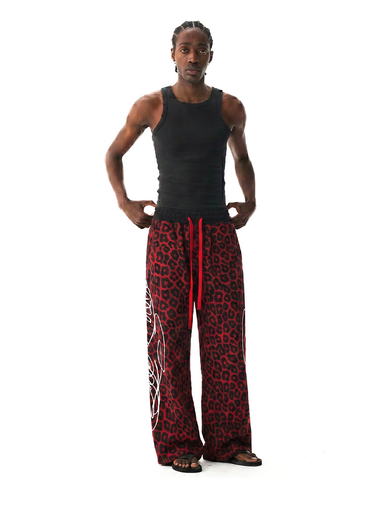 Model wearing a black tank top and red leopard print pants on a white background
