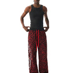 Model wearing a black tank top and red leopard print pants on a white background