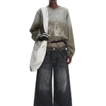 Front view of a model wearing dark charcoal wash wide-leg jeans with a long-sleeve grey top and white shoulder bag.