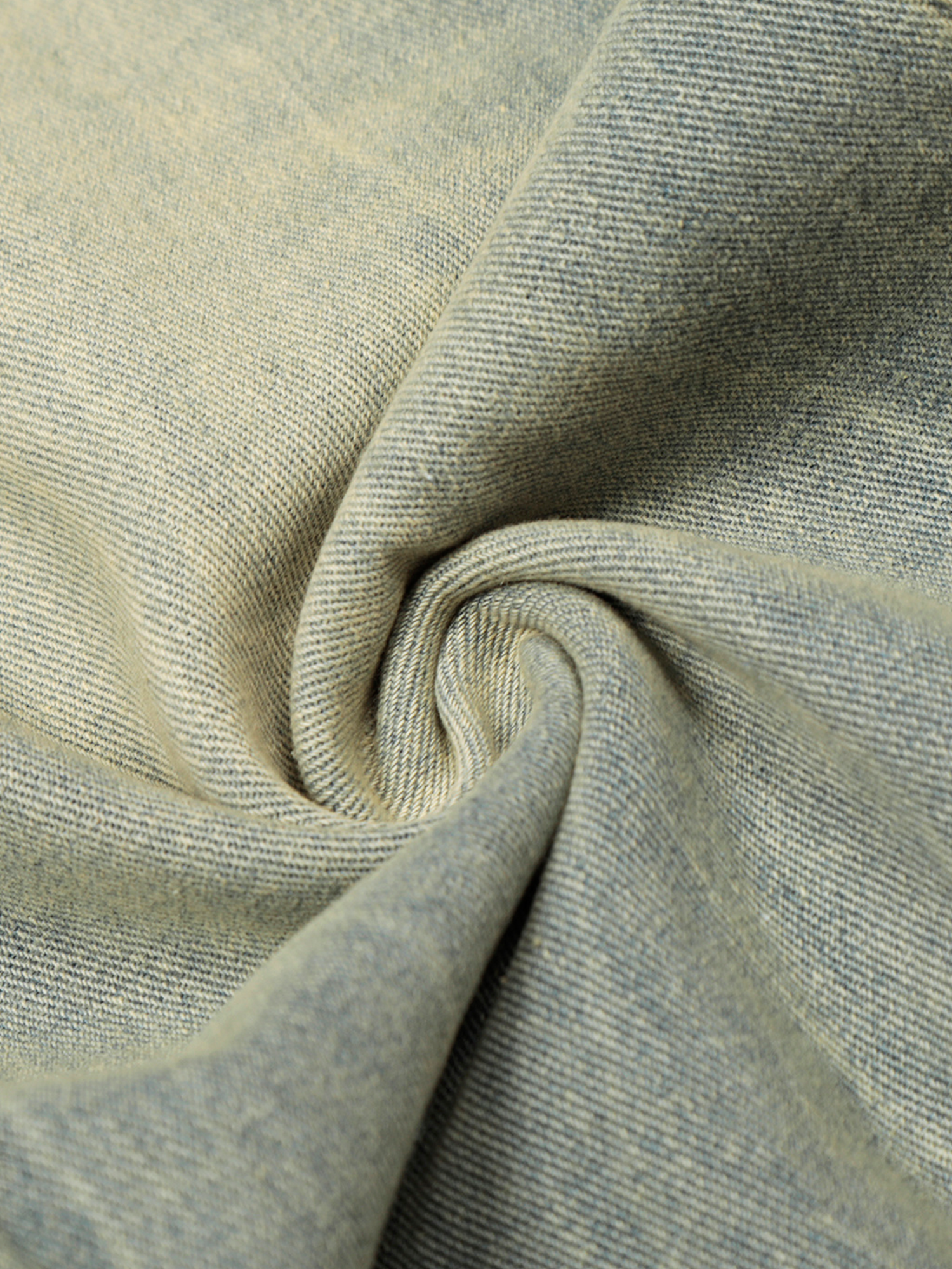 Plan rapproché de la texture d'un tissu en denim lavé clair, montrant la trame et les déchirures subtiles.