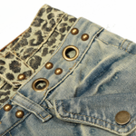 Close-up detail of the double-layered waistband on light wash jeans, featuring leopard print trim and metal grommet hardware.