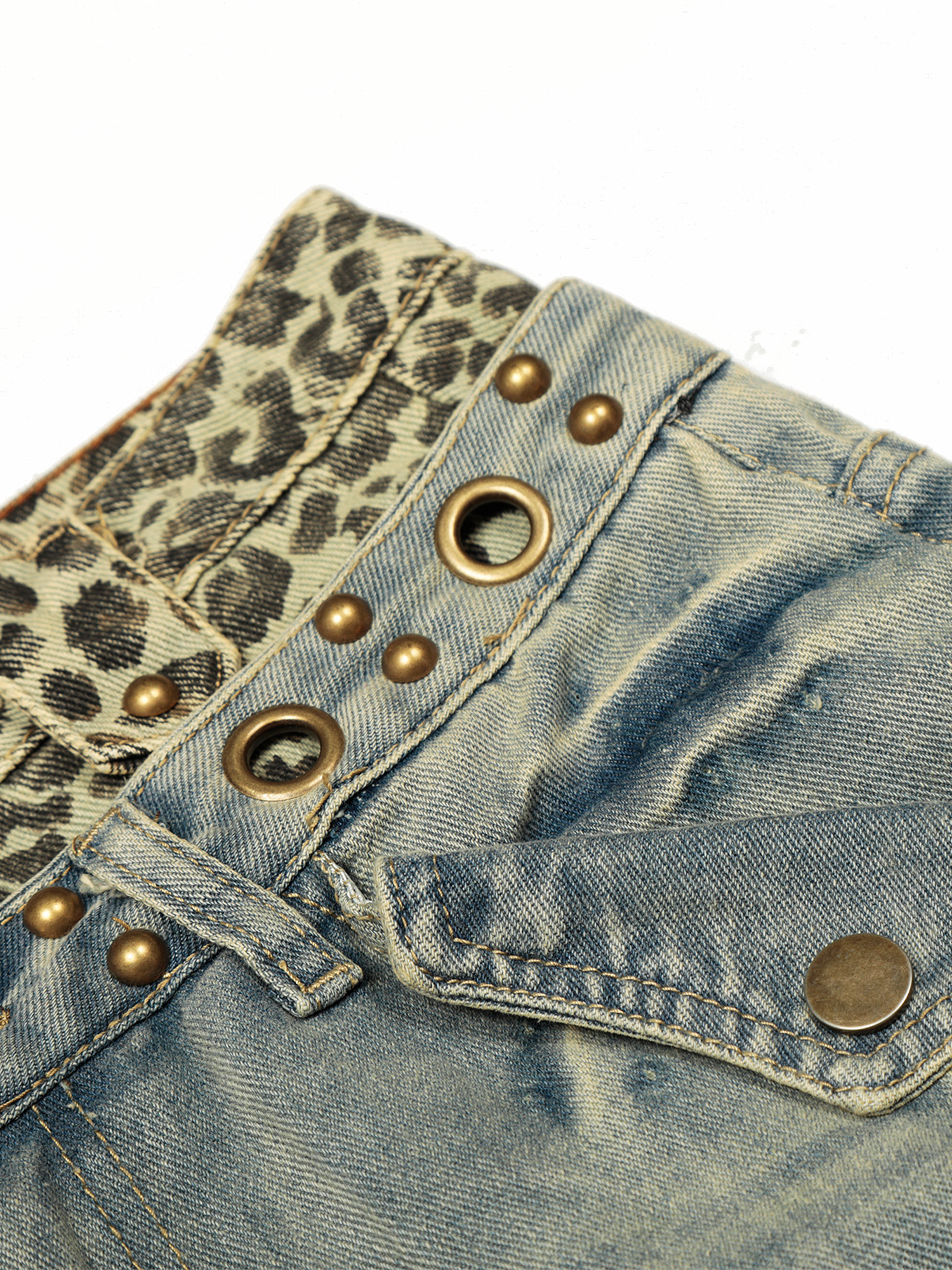 Détail en gros plan de la ceinture à double couche des jeans lavé clair, orné de bordures à imprimé léopard et d'œillets métalliques.