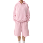 Full-body front view of a model wearing the same light pink hoodie and shorts set, paired with white socks and light-colored shoes.