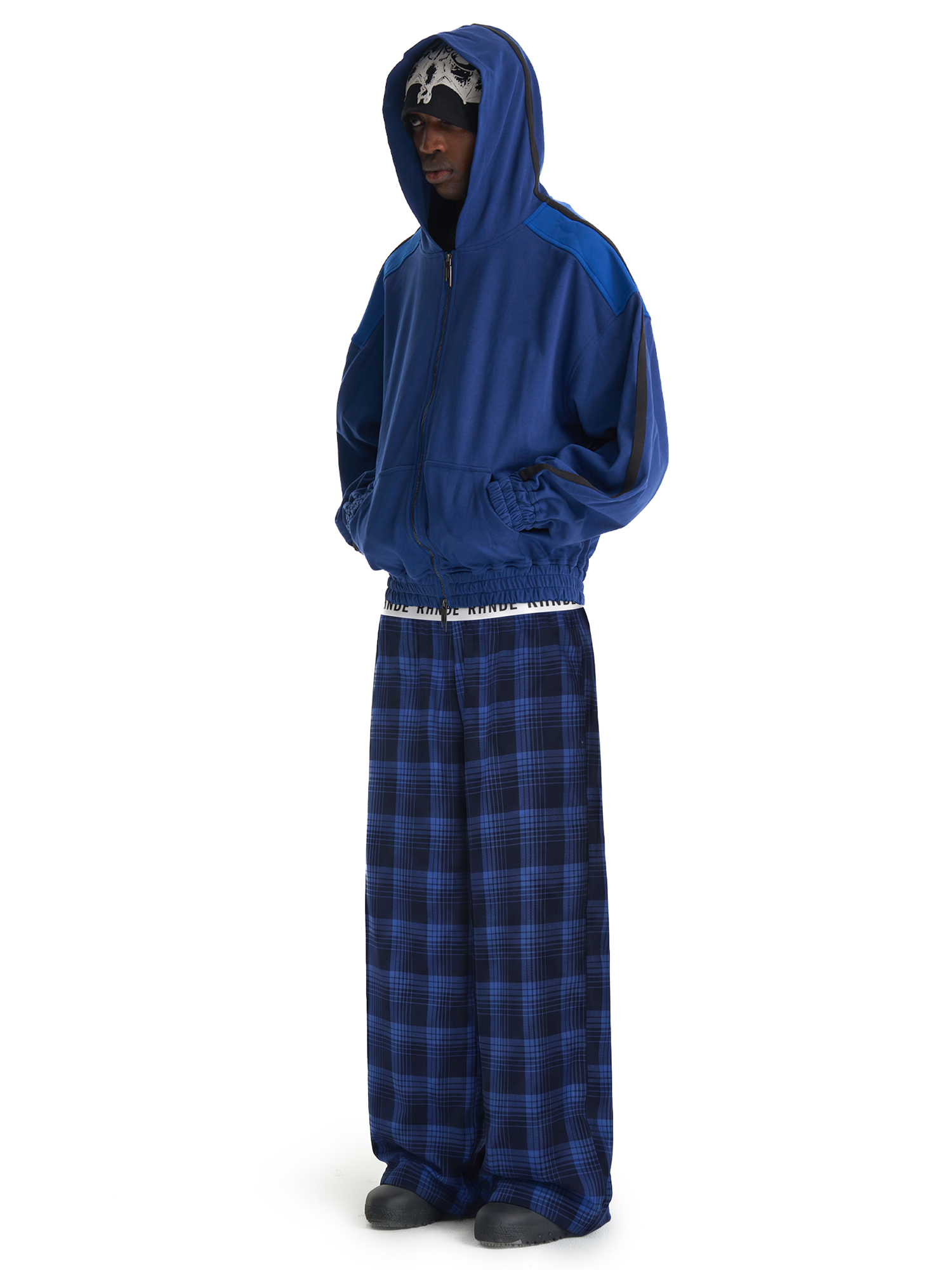 Side view of model styling blue checkered streetwear lounge pants with a relaxed baggy fit.
