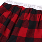 Close-up of white elastic waistband with bold black typography on plaid baggy pants.