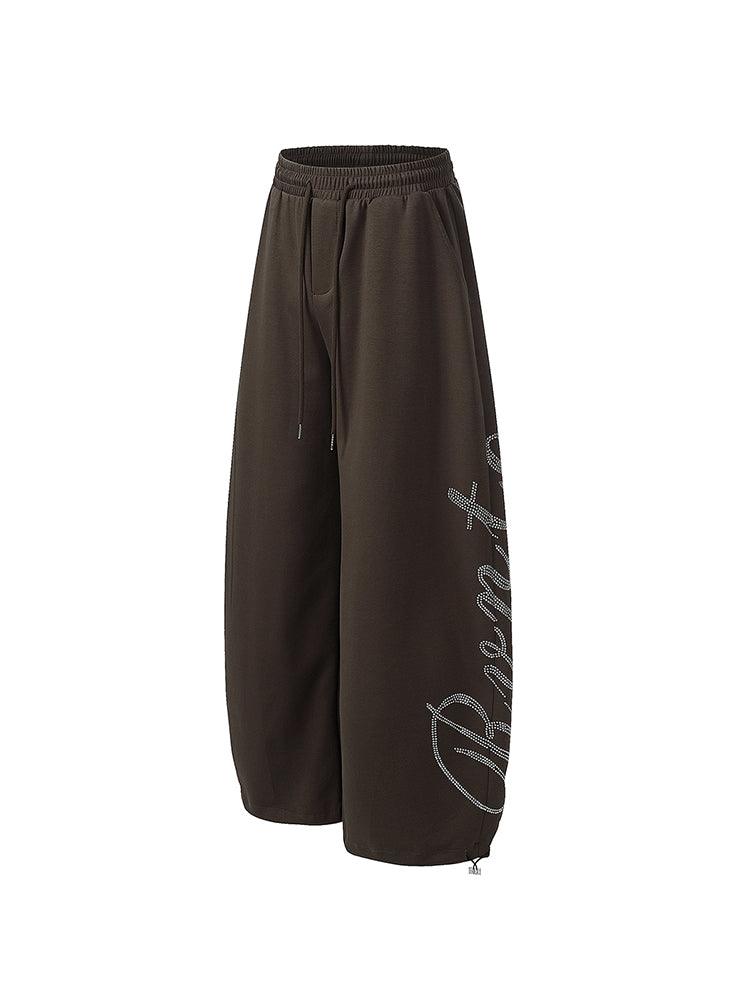 Profil latéral d'un pantalon de survêtement baggy marron foncé, montrant une coupe ample et un détail graphique