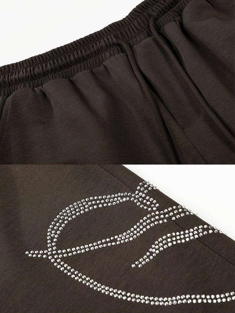 Detailed view of white screen-printed graphic on dark brown streetwear pants.