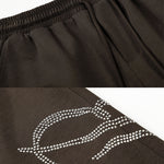 Detailed view of white screen-printed graphic on dark brown streetwear pants.
