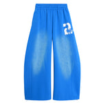 Front view of bright blue wide-leg track pants featuring a white graphic print with the number "2" on the leg.